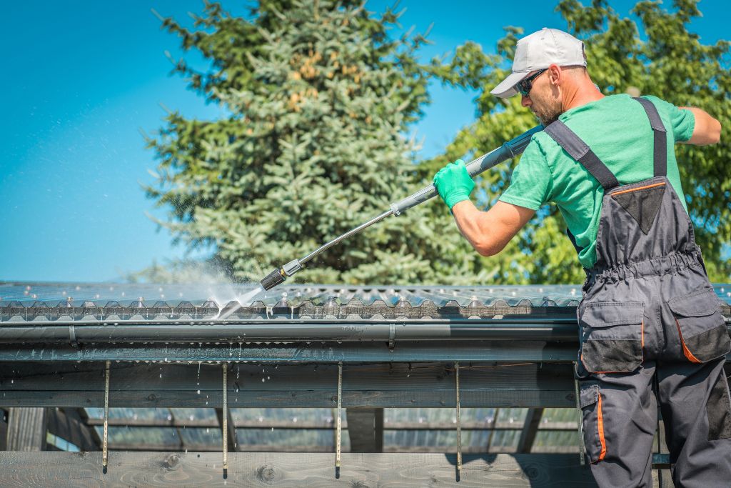 Worker cleaning the gutters of a house