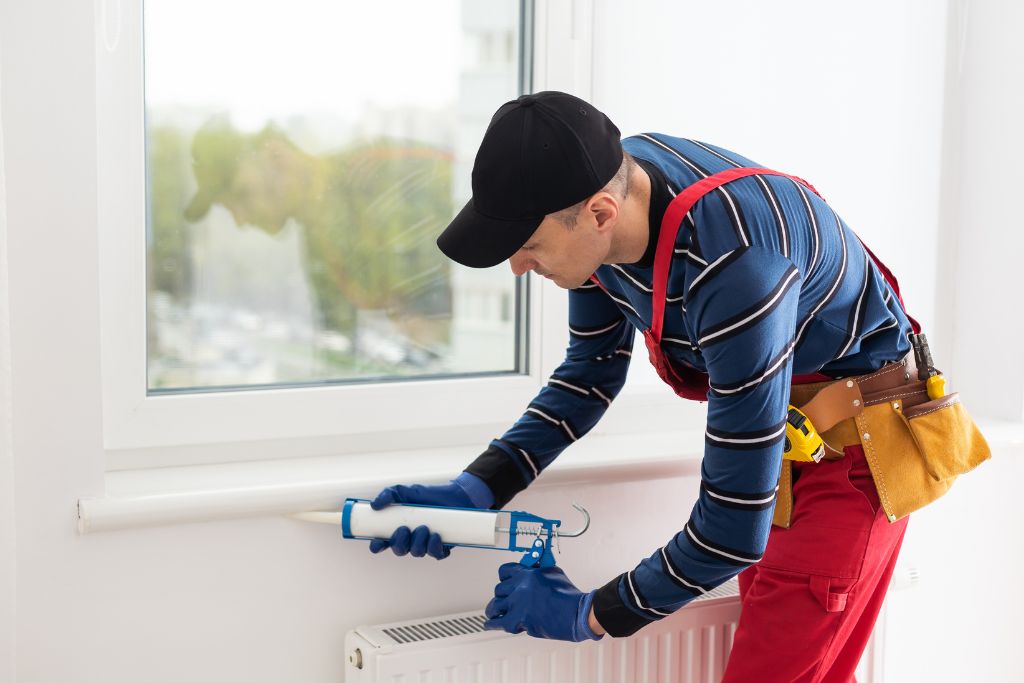 Construction worker applying caulking to exterior window