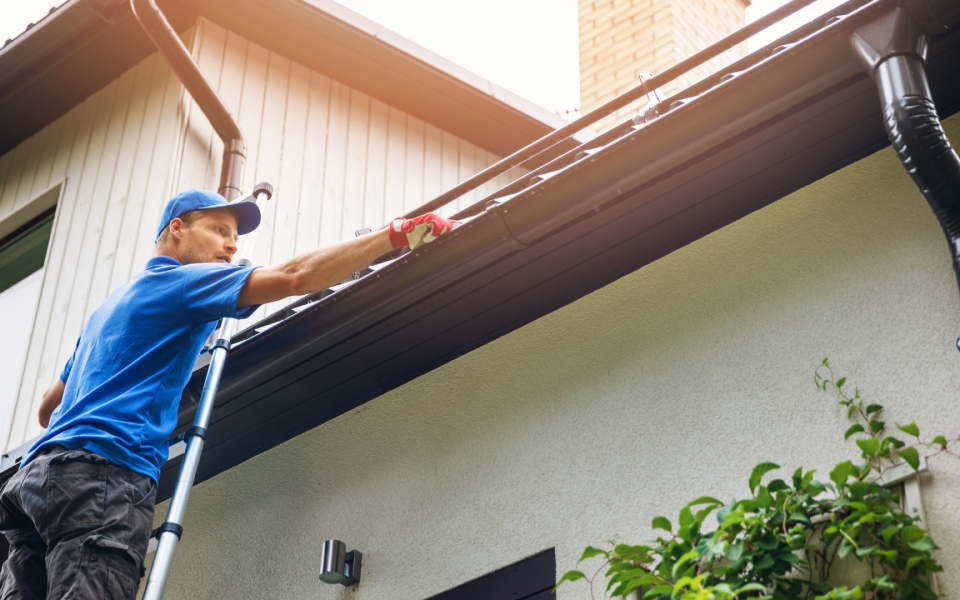 Professional cleaner cleaning clogged eavestrough