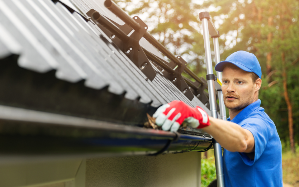 Professional cleaner cleaning clogged eavestrough